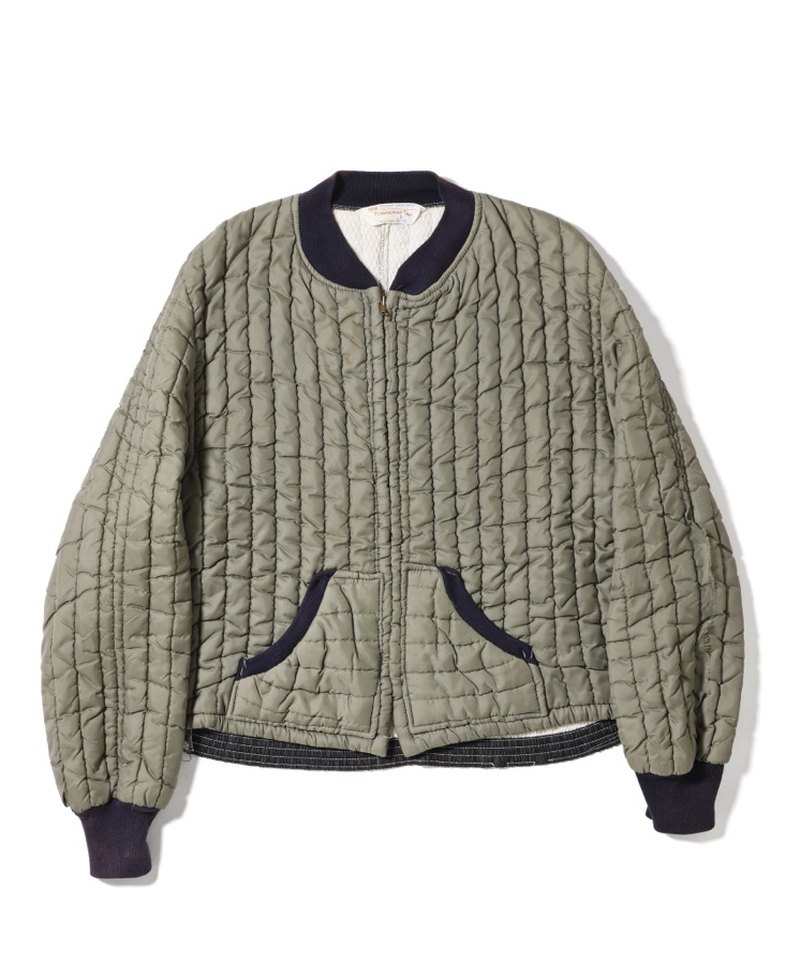 Front of a vintage quilted jacket with a navy rib-knit collar and cuffs, a front zipper and curved pockets on the left and right at the waist